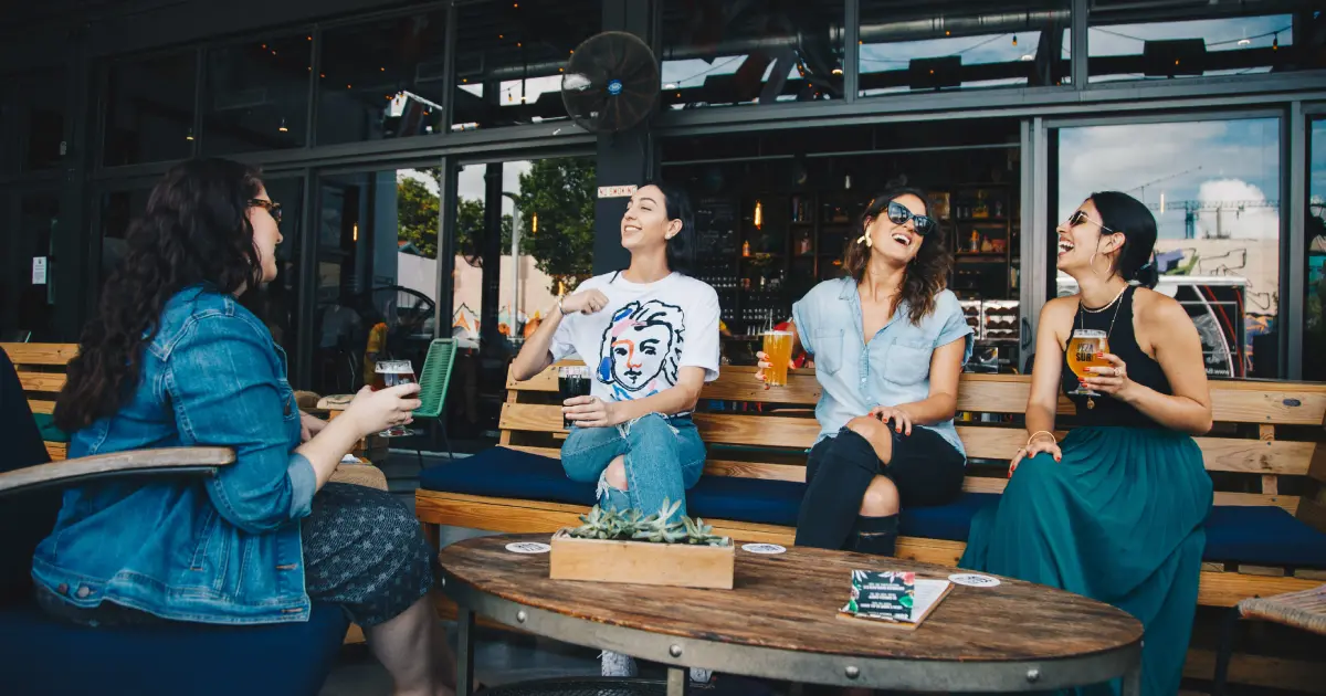 4 mulheres conversando sentadas em um banco usando inglês para viagem