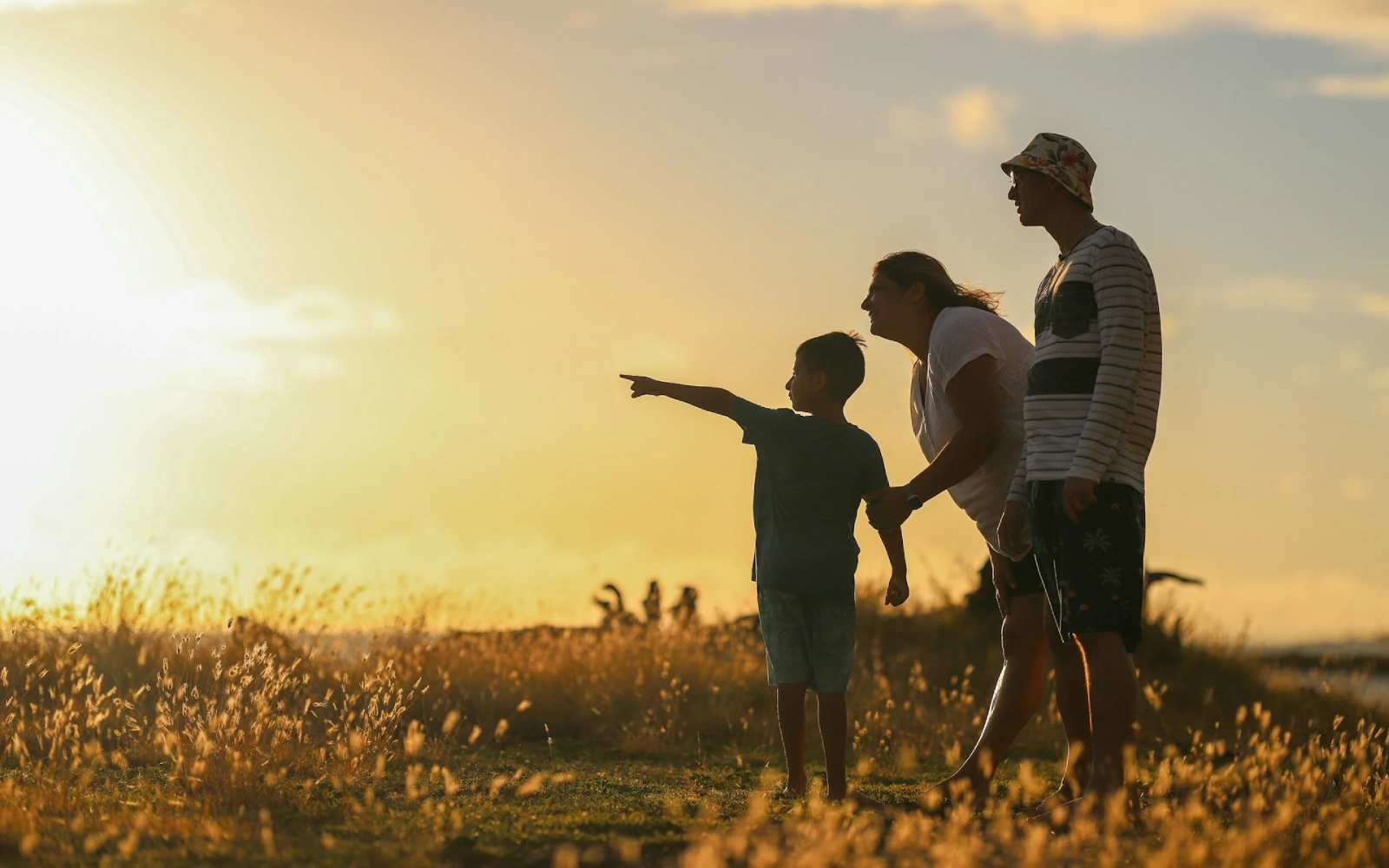 Homem e mulher de mãos dadas enquanto caminham de mãos dadas no campo durante o pôr-do-sol