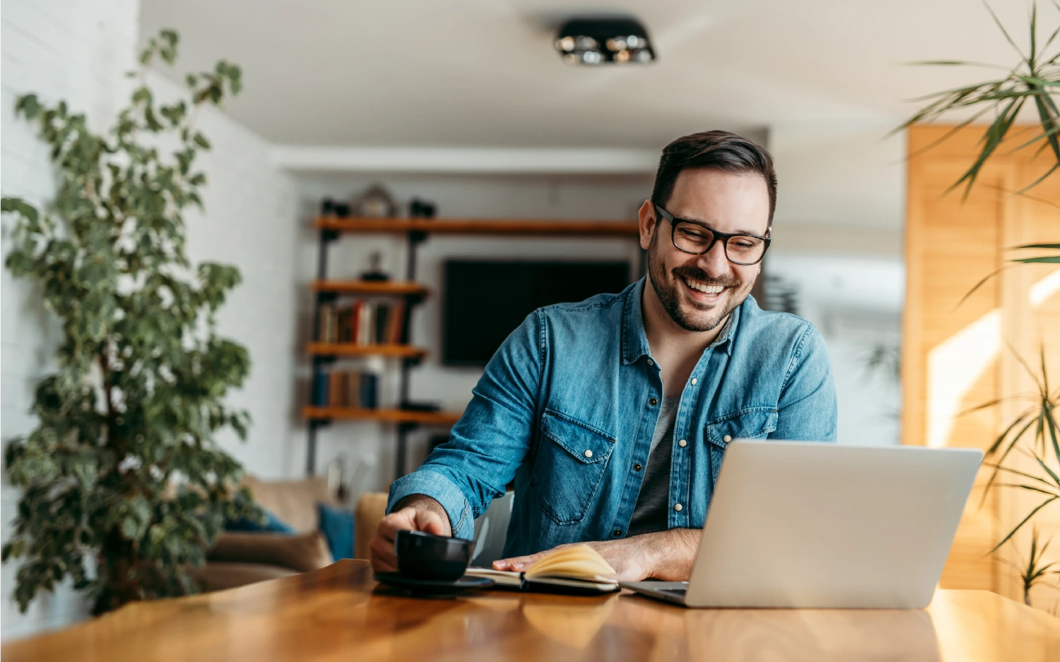 Homem de óculos e camisa azul usando um notebook