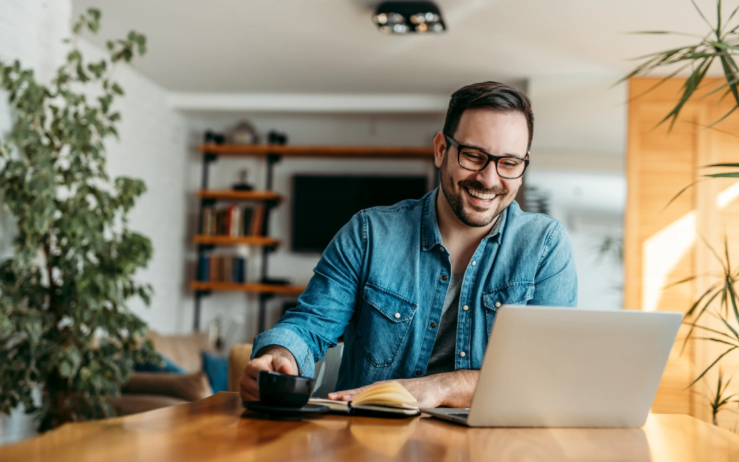 Homem sorridente usando notebook na mesa