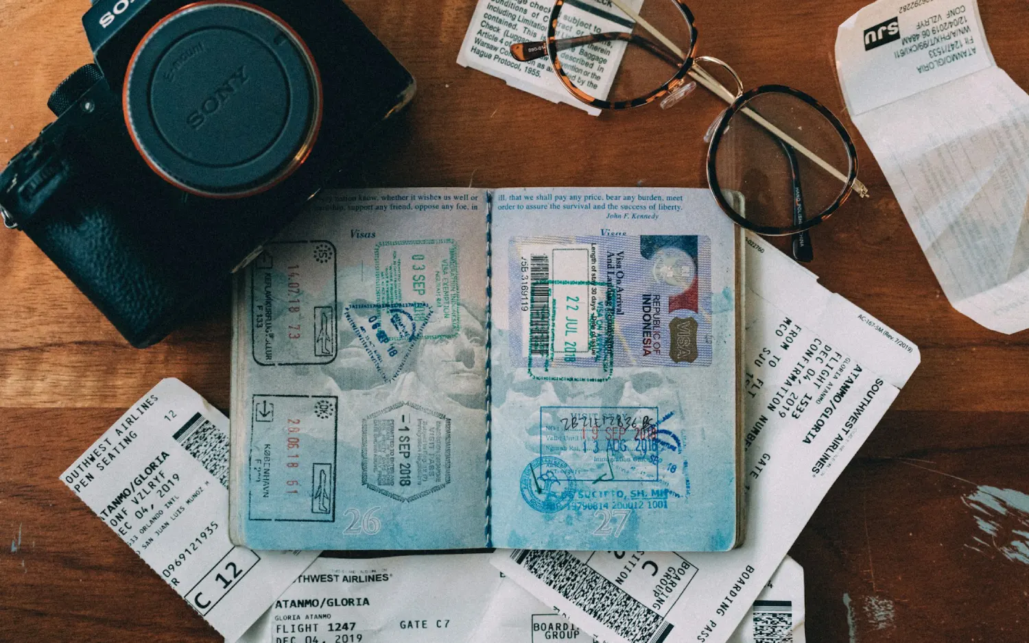 Passaporte sobre uma mesa ao lado de câmera fotográfica e cadernos