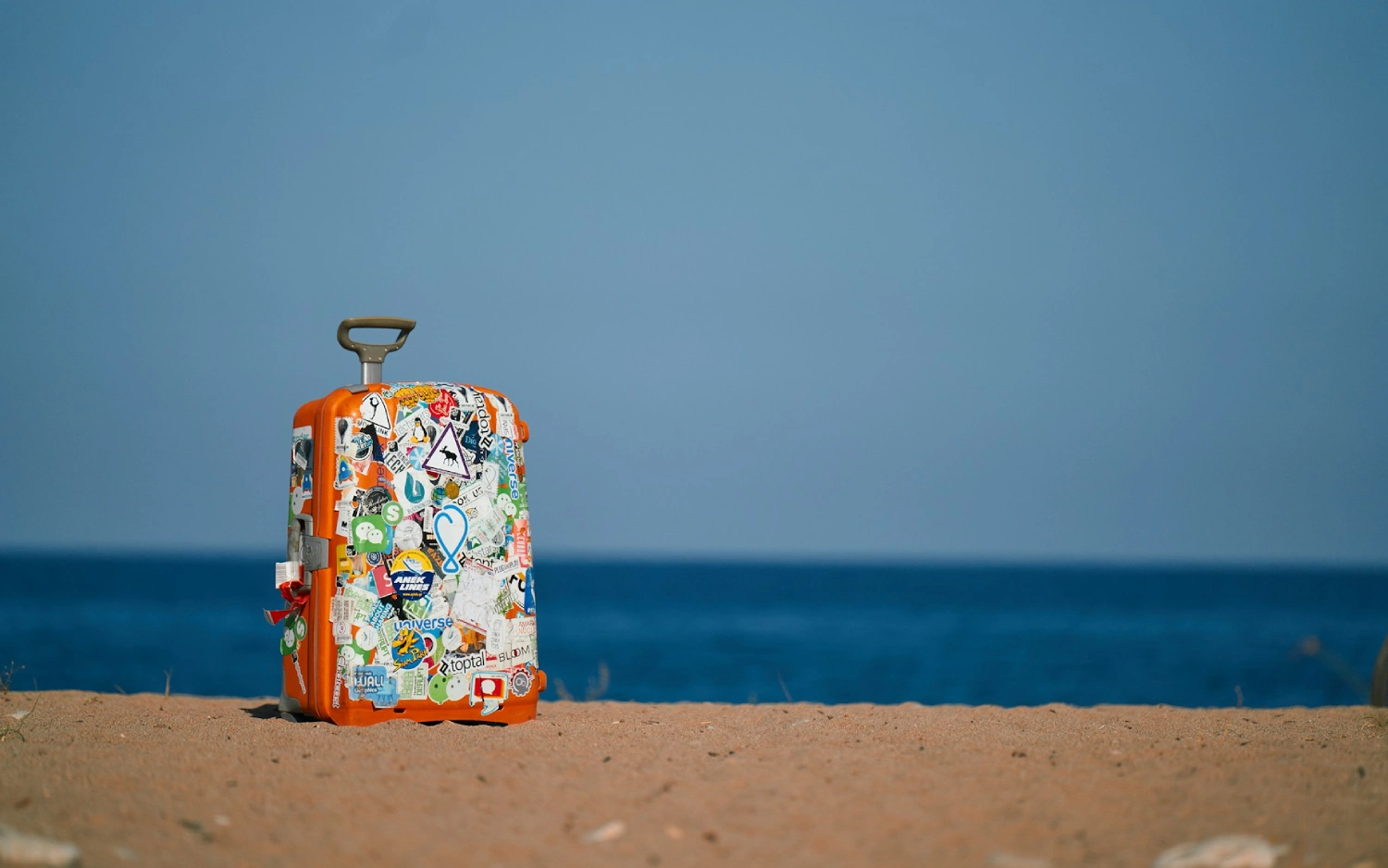 Mala com adesivos em praia