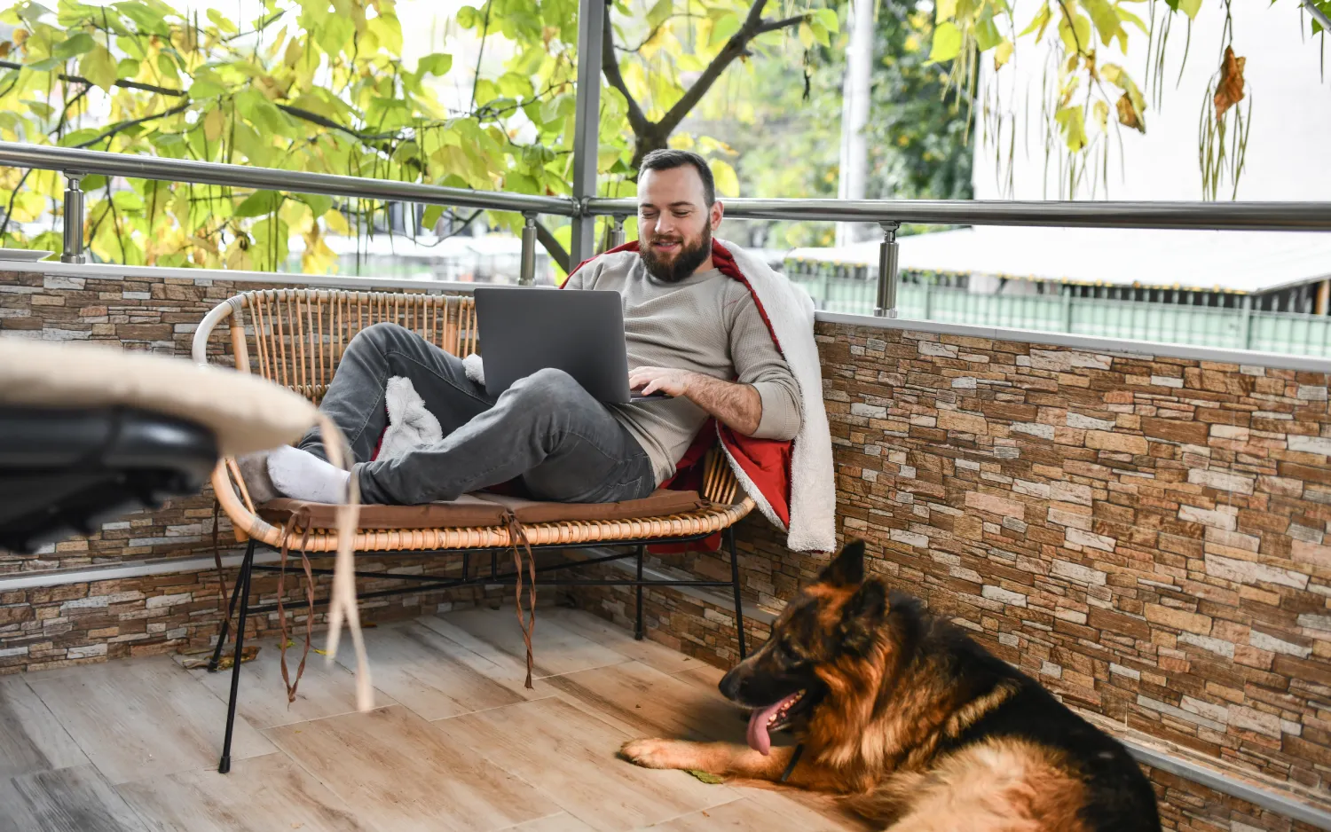 Homem relaxando em cadeira em jardim com notebook no colo