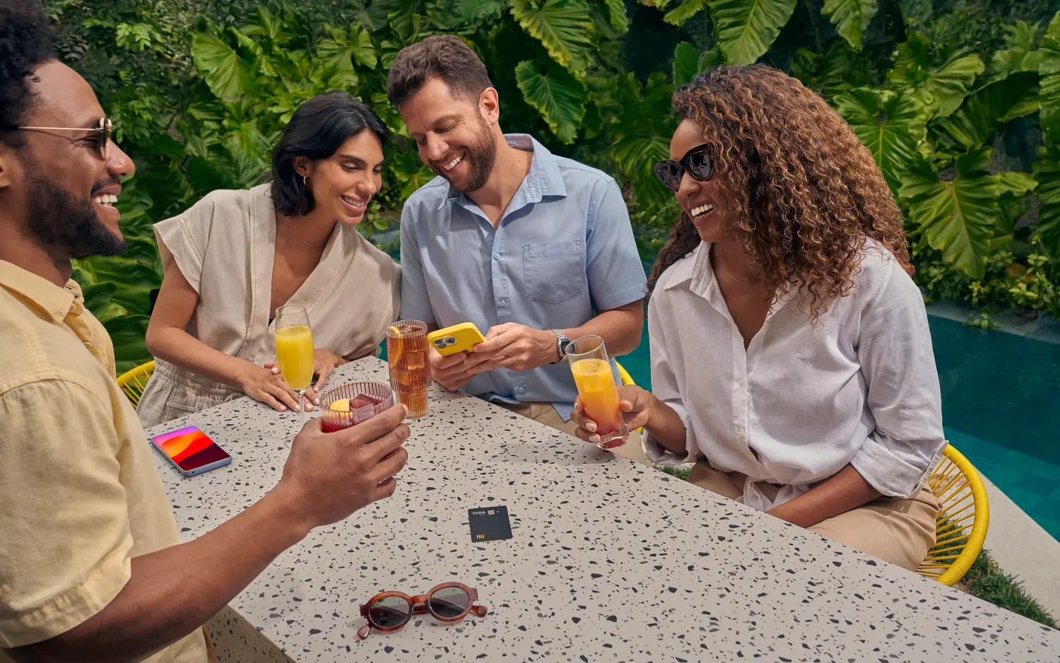 Grupo de pessoas ao redor de mesa rindo e bebendo