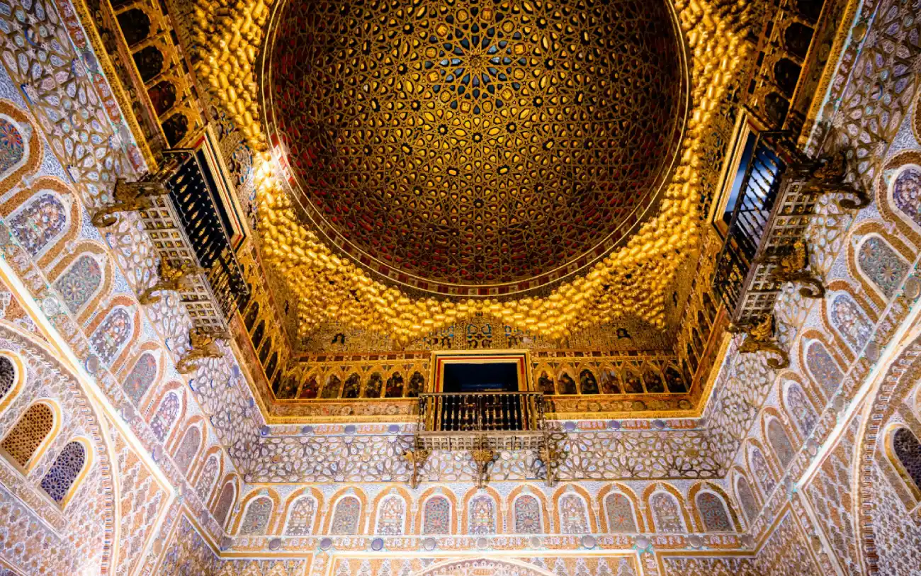 Interior do Real Alcazar de Sevilha com cúpula e paredes adornados com azulejos mouriscos