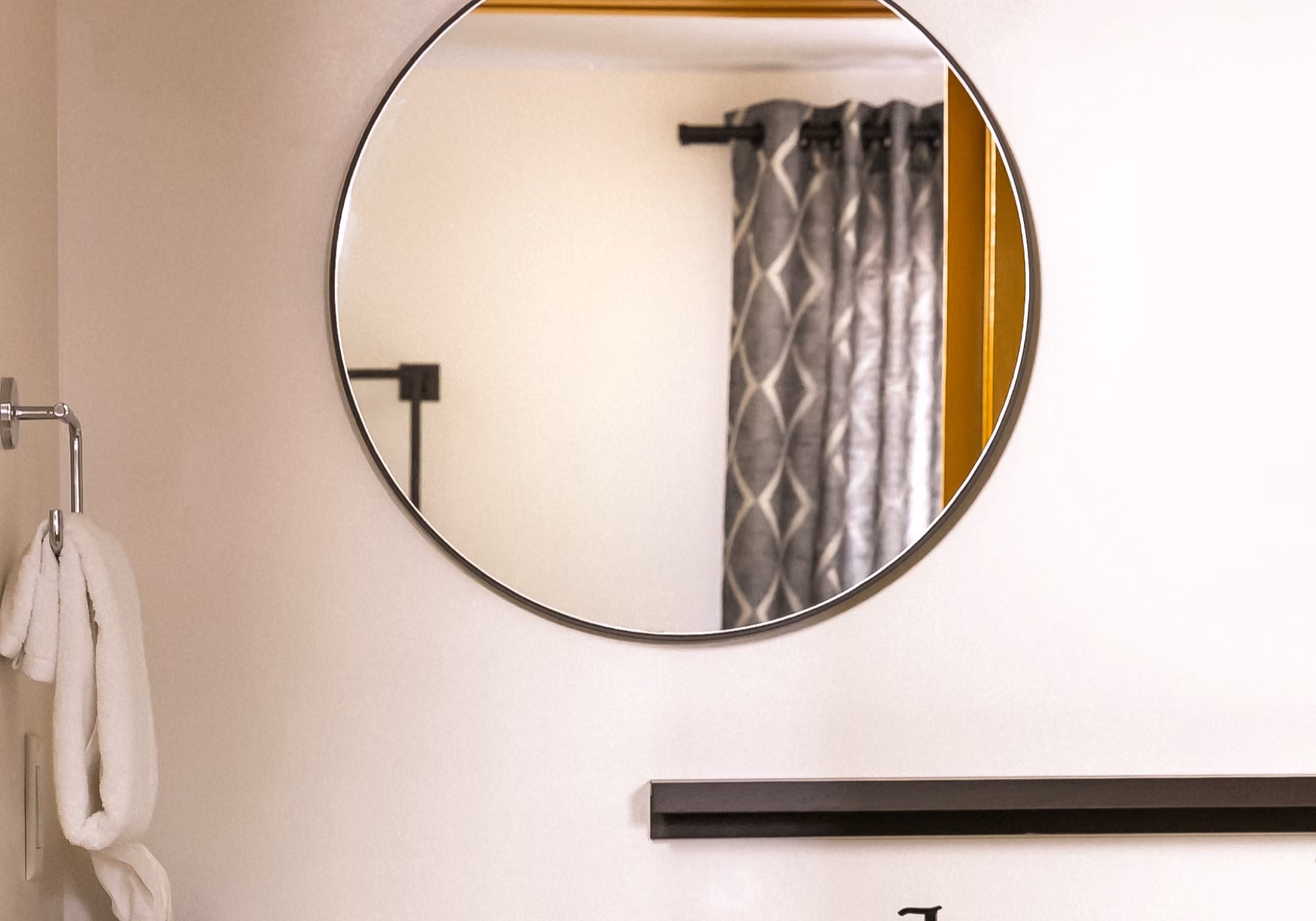 Round bathroom mirror and fresh towels in a two-bedroom suite bathroom