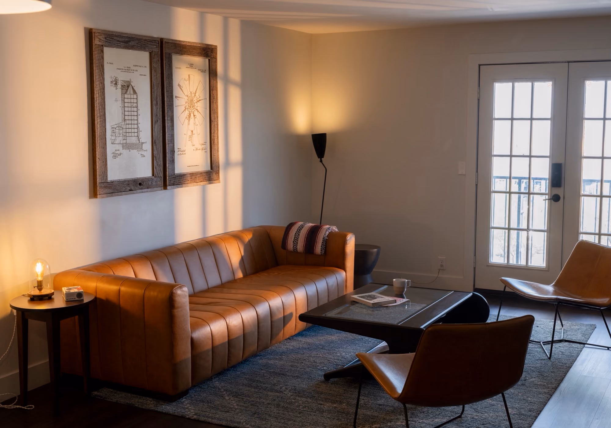 Living room with tan leather sofa, coffee table and French doors in a two-bedroom premium suite