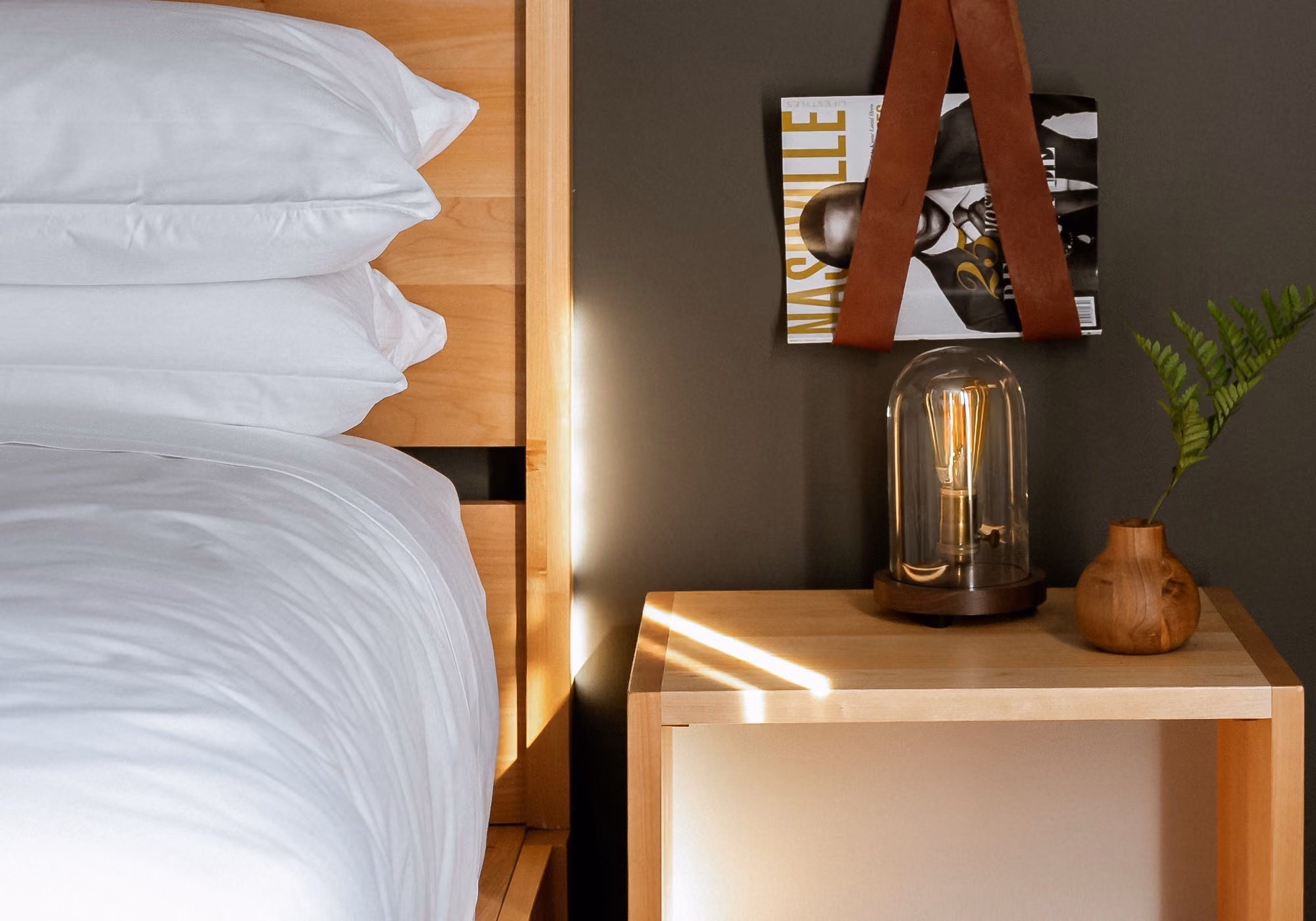 Bedside table with Edison lamp and Nashville magazine beside a bed in a two-bedroom premium suite