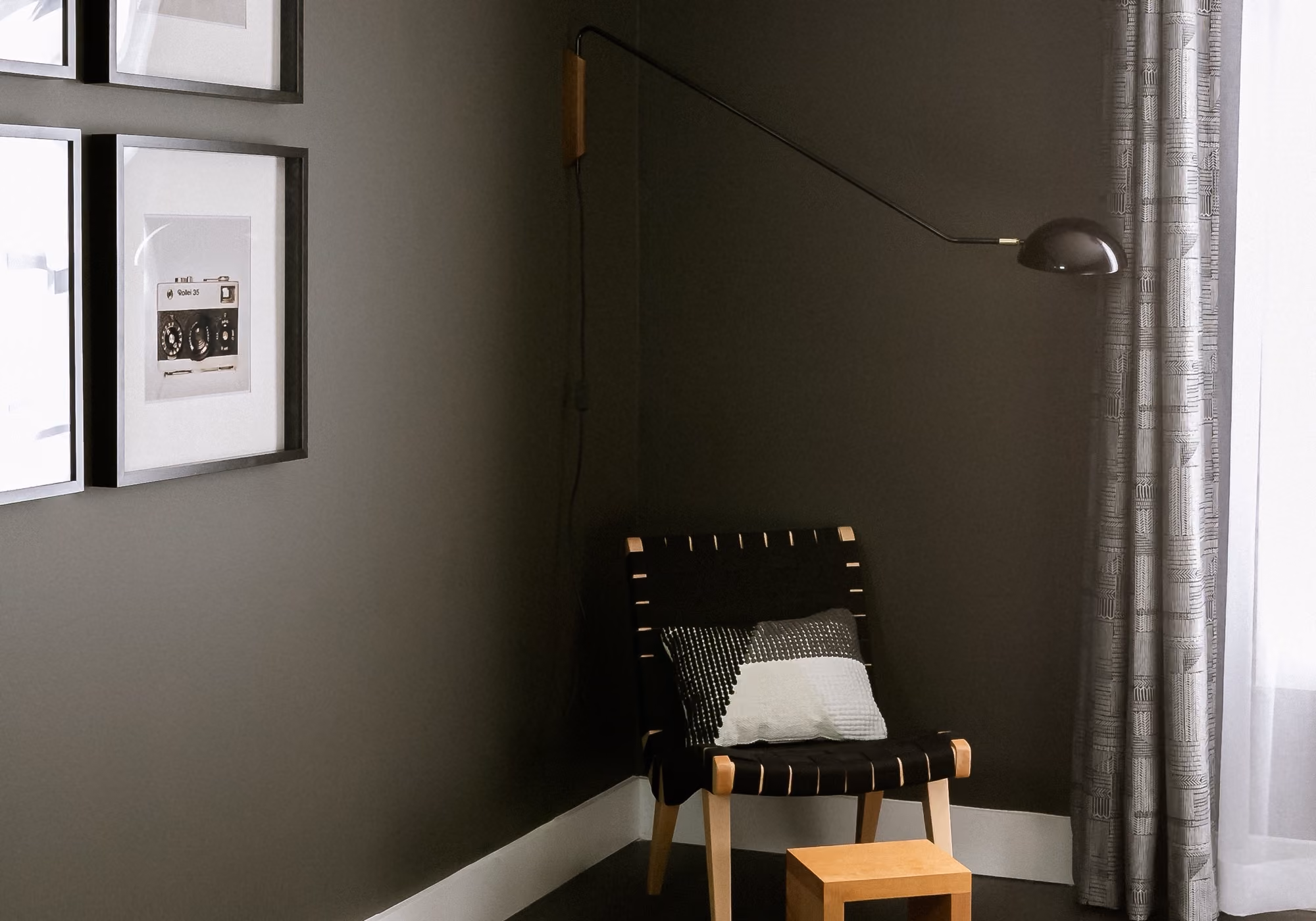 Reading corner with woven lounge chair, wall lamp and framed art in a two-bedroom premium suite