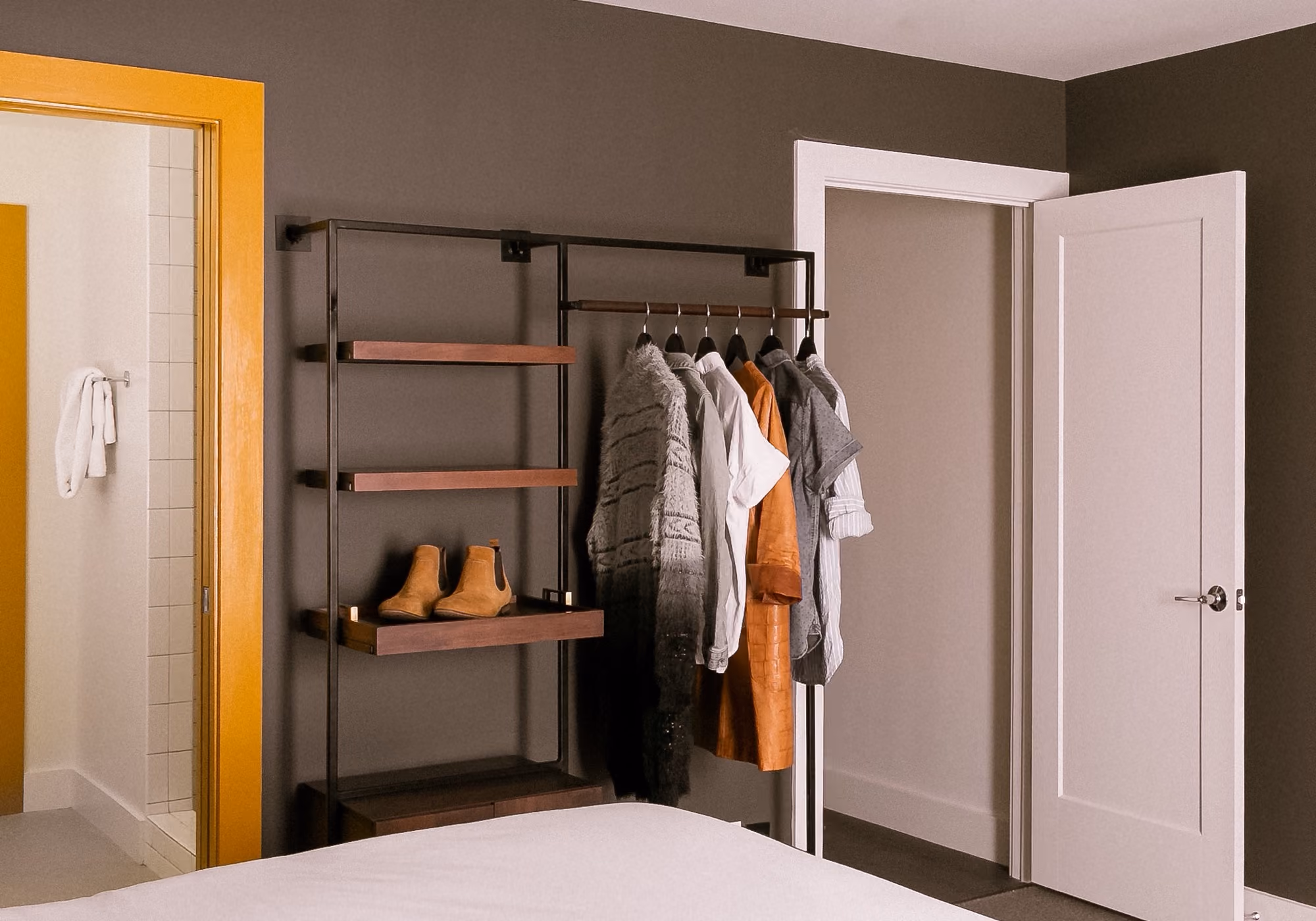 Open wardrobe rack with wooden shelves beside the bathroom in a three-bedroom suite bedroom