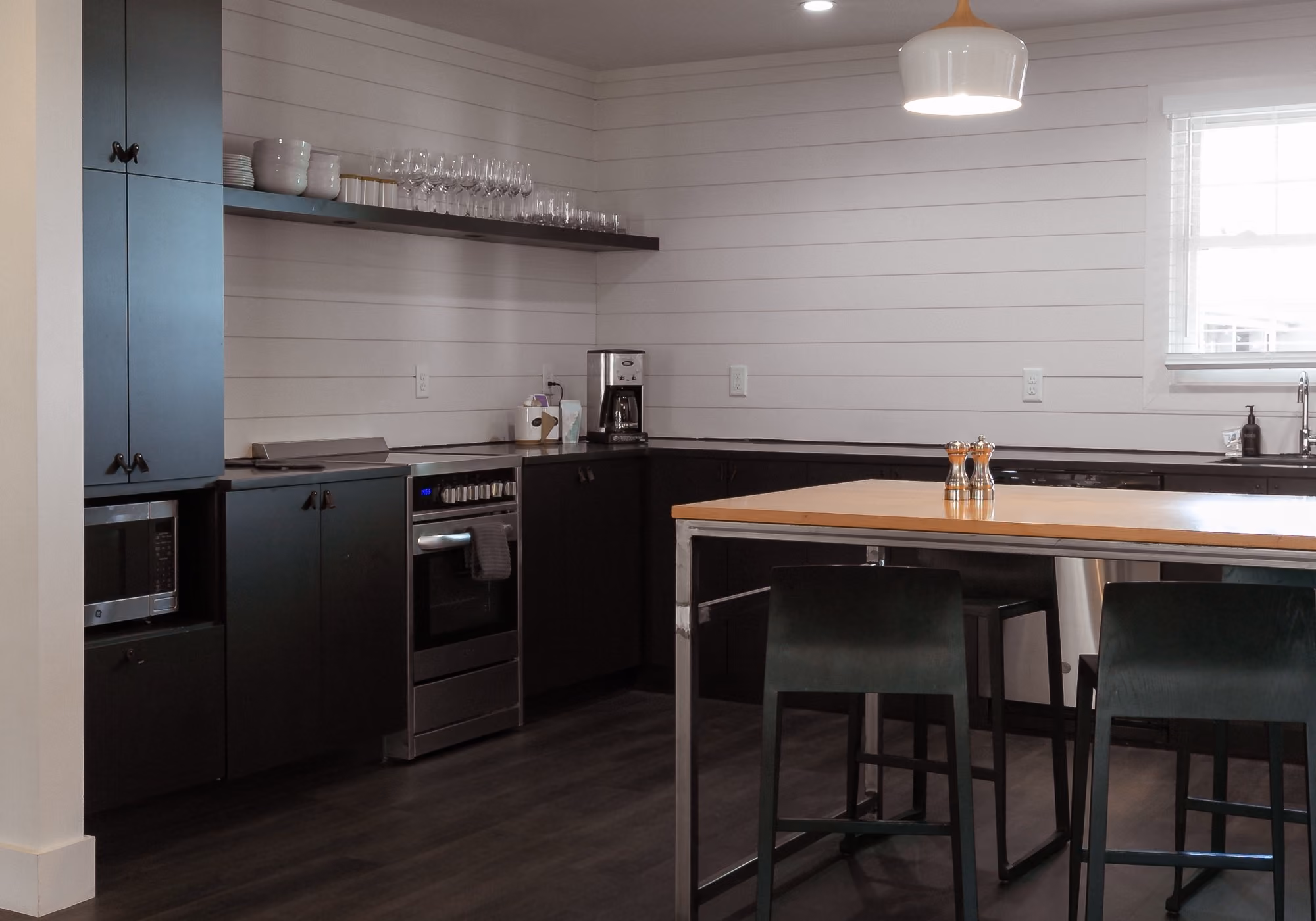 Kitchen with black cabinets, island seating and full appliances in a four-bedroom suite