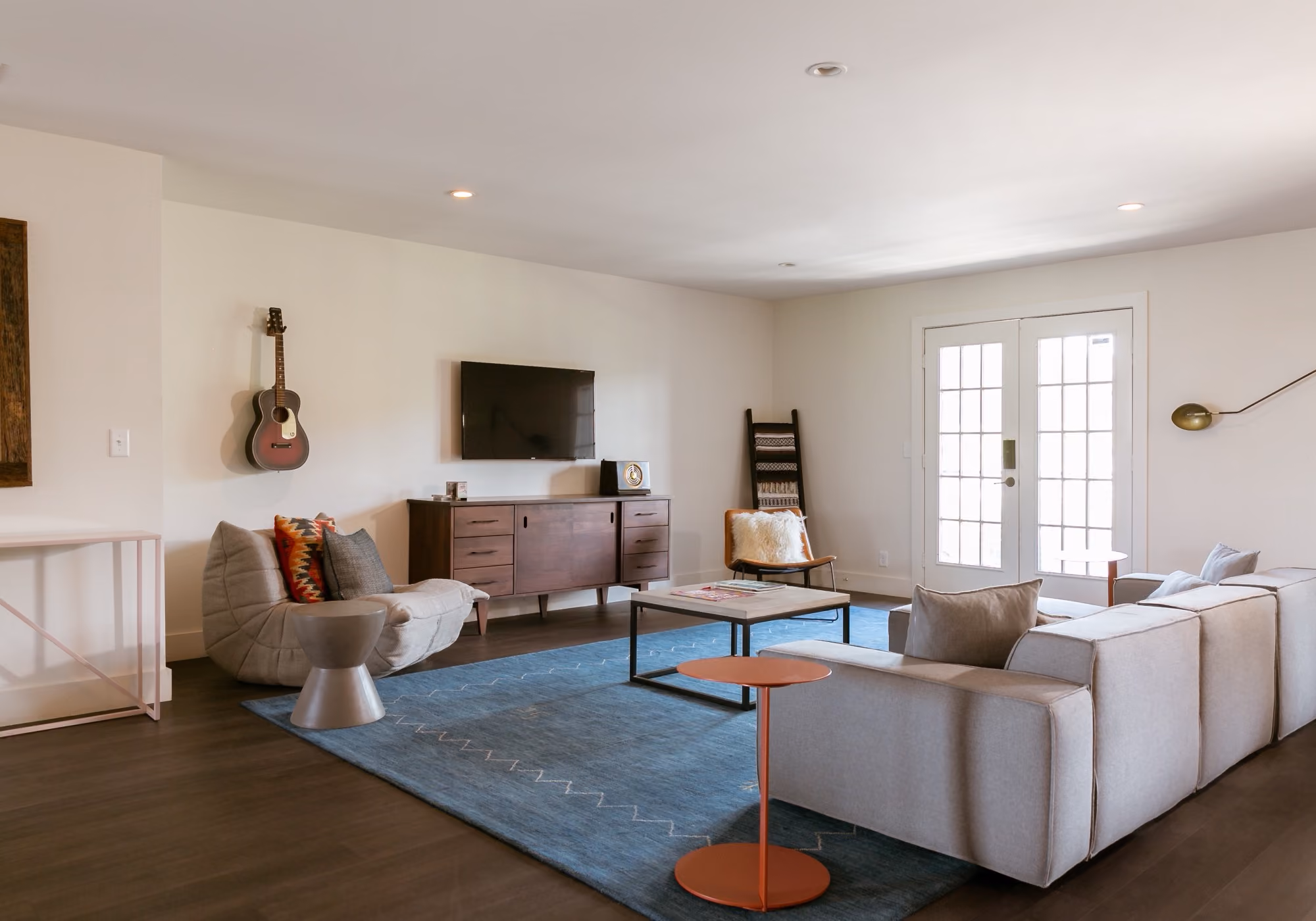 Spacious living room with sectional sofa, wall-mounted TV and guitar in a four-bedroom suite