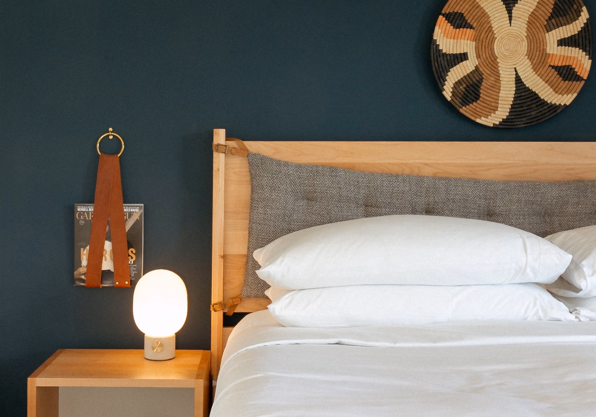 King bed with wooden frame and woven wall art against a teal wall in a four-bedroom suite bedroom