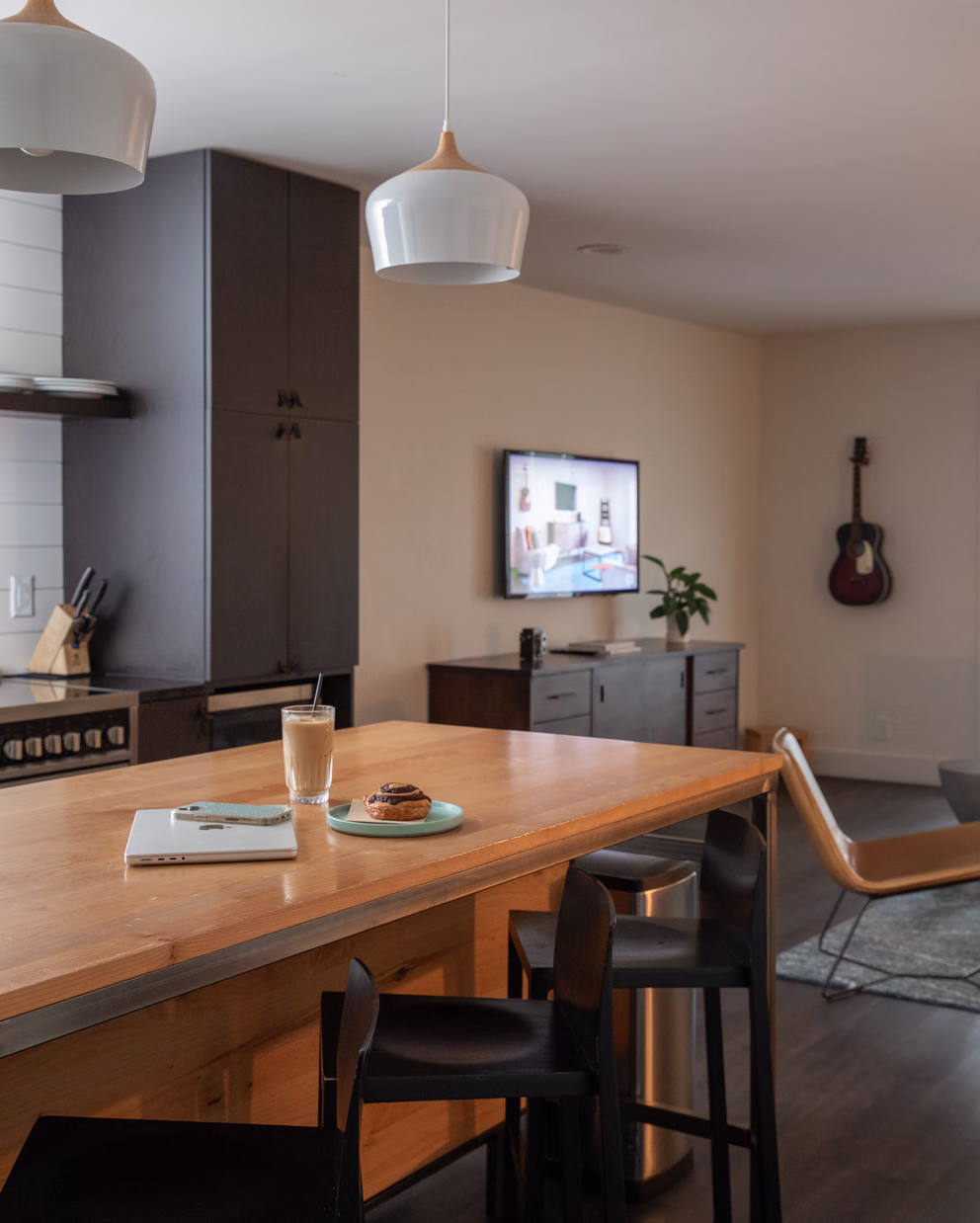 Bode Nashville suite kitchen with a wood island, bar stools, and a guitar on the wall