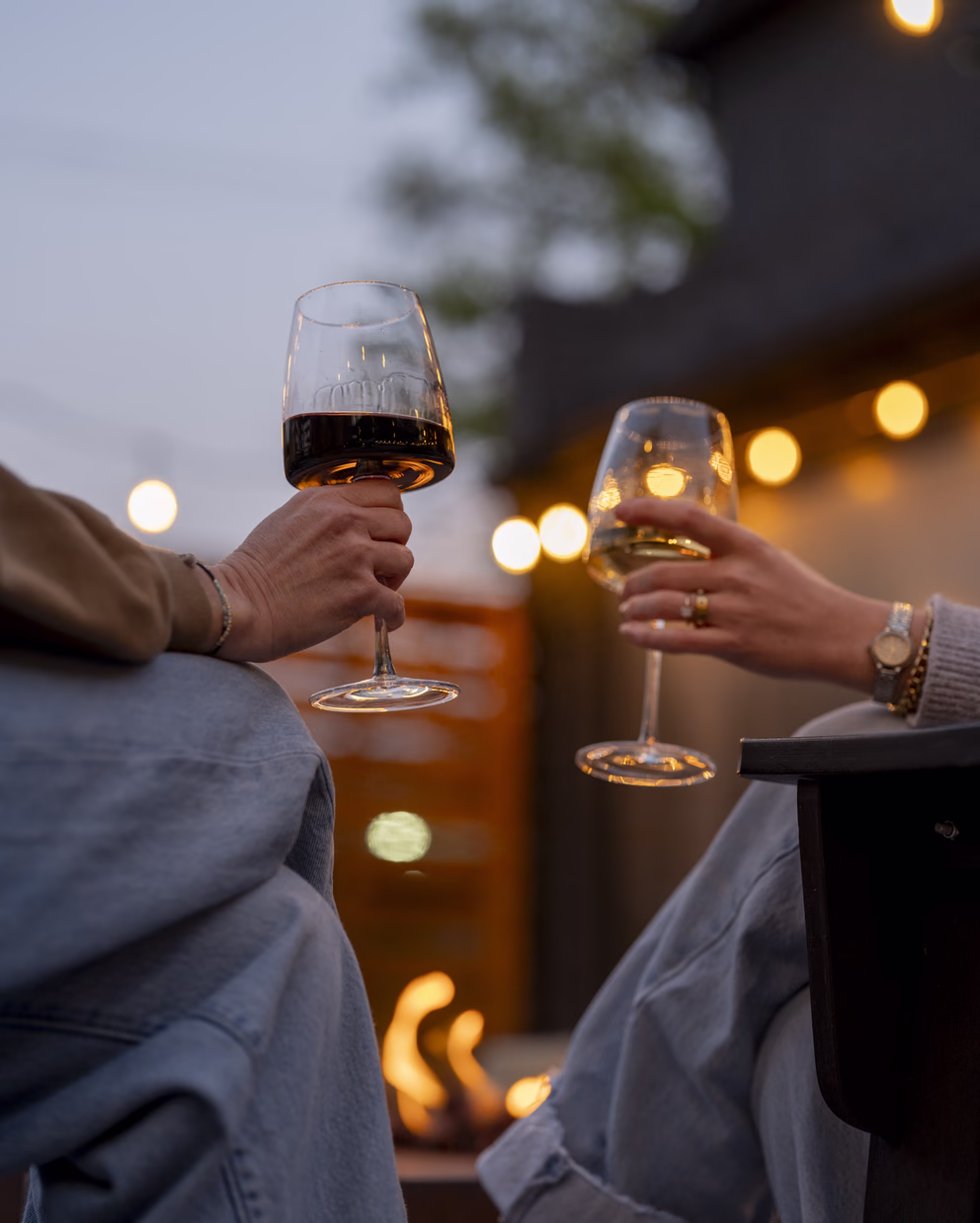Guests sharing glasses of wine by a fire pit under string lights at Bode Nashville