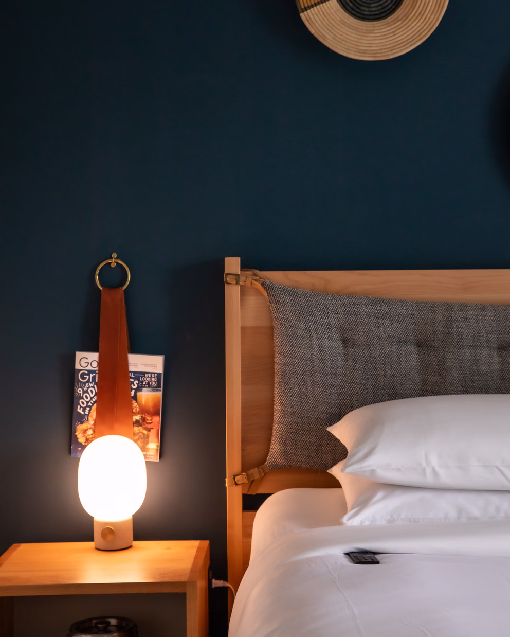 Bode Nashville bedroom with a teal accent wall, white linens, and a leather-strap bedside lamp