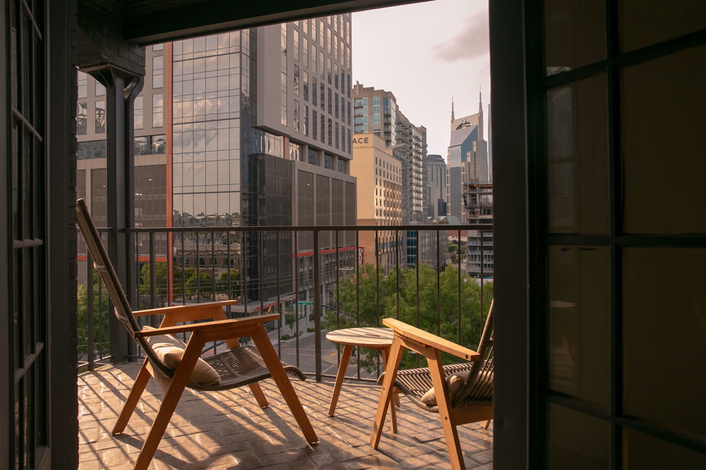 Private balcony with wooden lounge chairs overlooking the downtown Nashville skyline at Bode Nashville