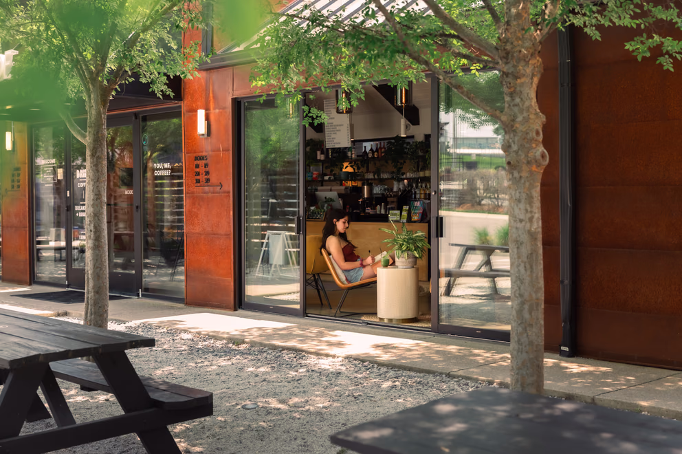 Dawn cafe storefront and picnic tables in the tree-lined Bode Nashville courtyard