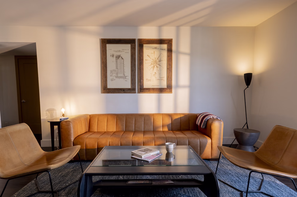 Bode Nashville suite living room with a cognac leather sofa, glass coffee table, and framed art
