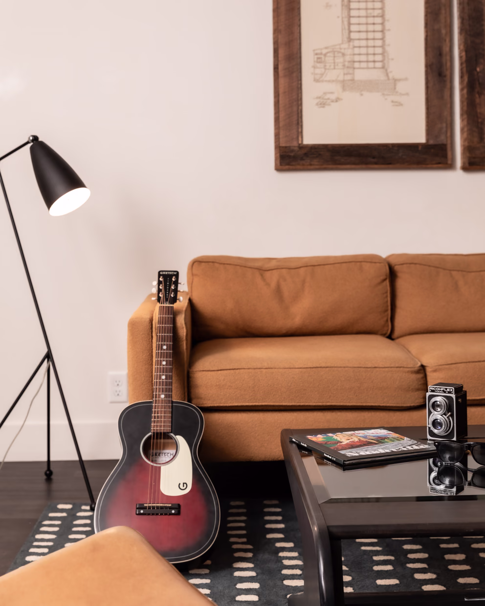 Bode Nashville suite lounge with an acoustic guitar, leather sofa, and black floor lamp