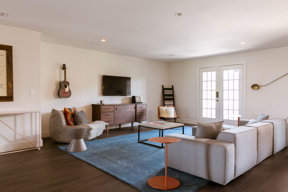 Spacious Bode Nashville suite living room with a white sectional sofa and blue area rug