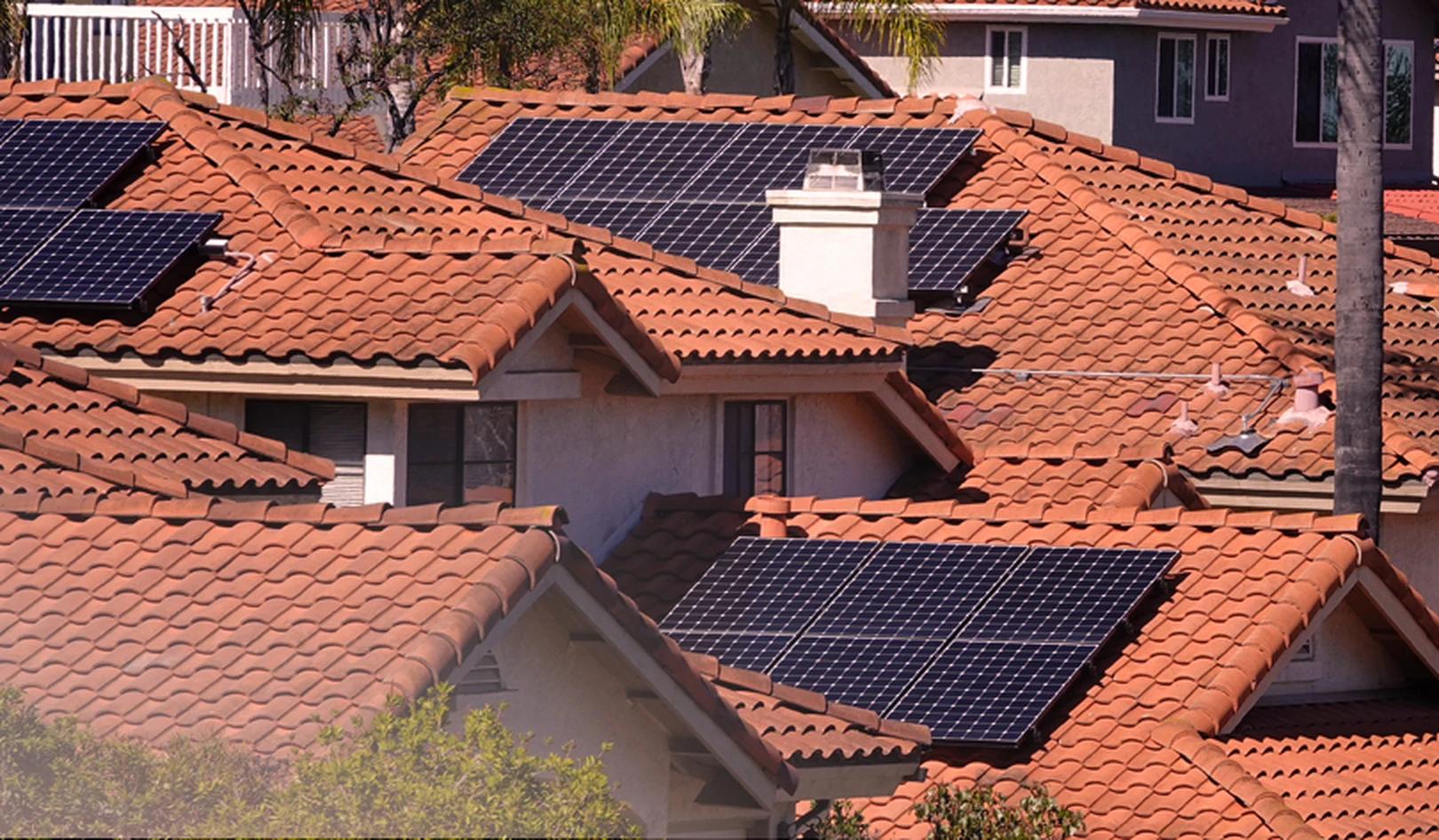 This is a picture of rooftop solar panels on several Spanish-style roofs of homes in California.