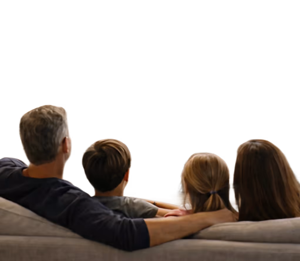 Family of four sitting on a couch viewed from behind, looking forward.