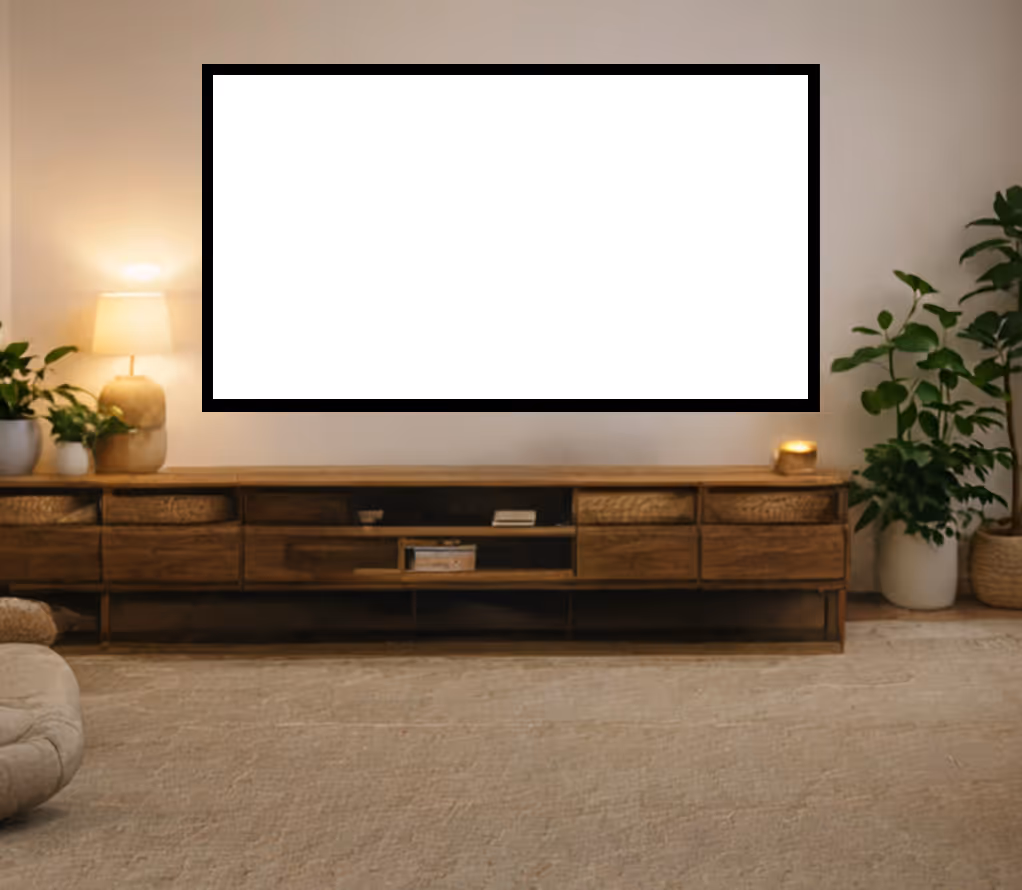 Modern living room with a blank large TV screen mounted on the wall above a wooden media console, decorated with plants and a lit table lamp.