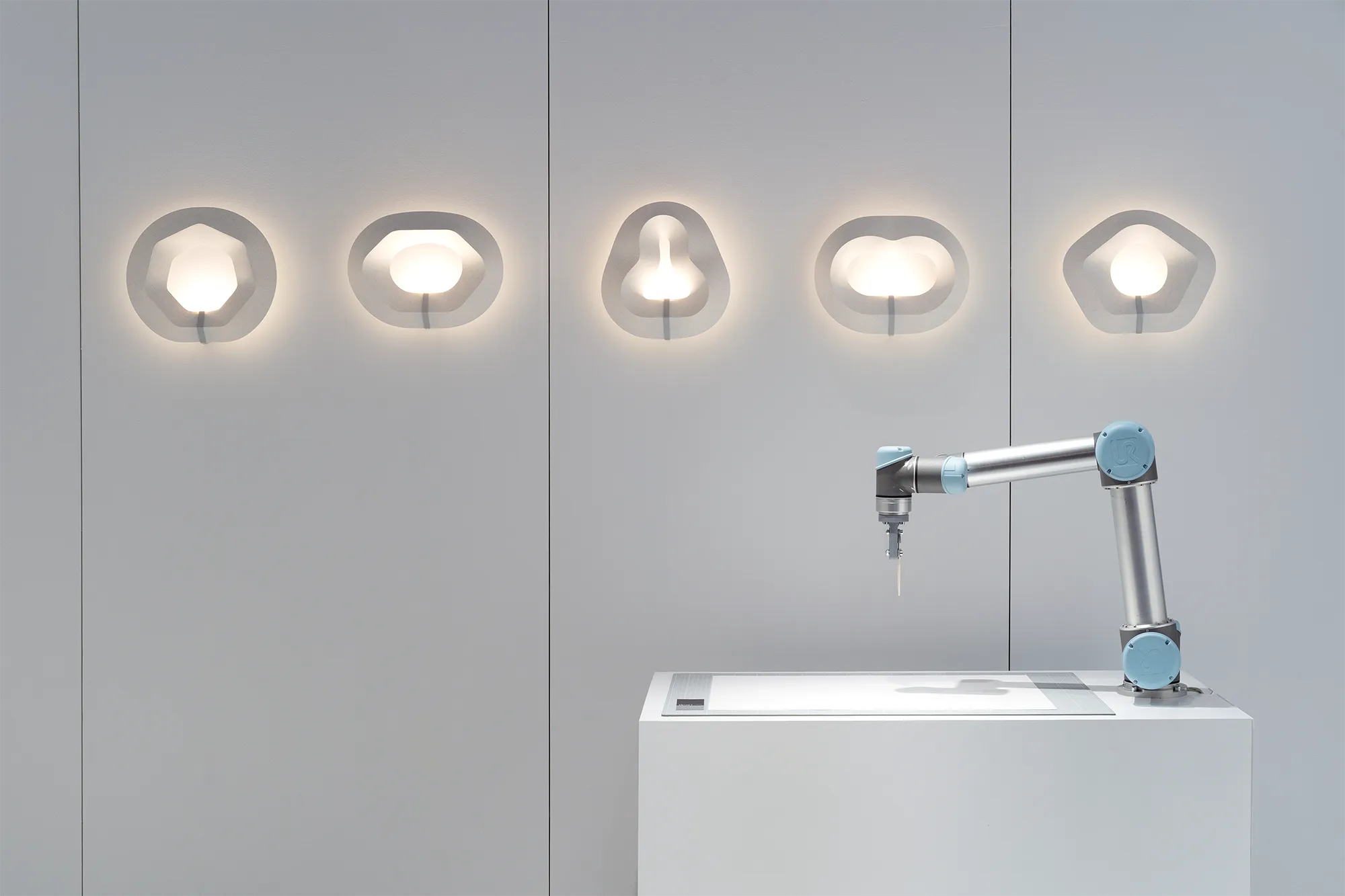 Robot arm standing on a table to fold paper with paper prototypes in the foreground