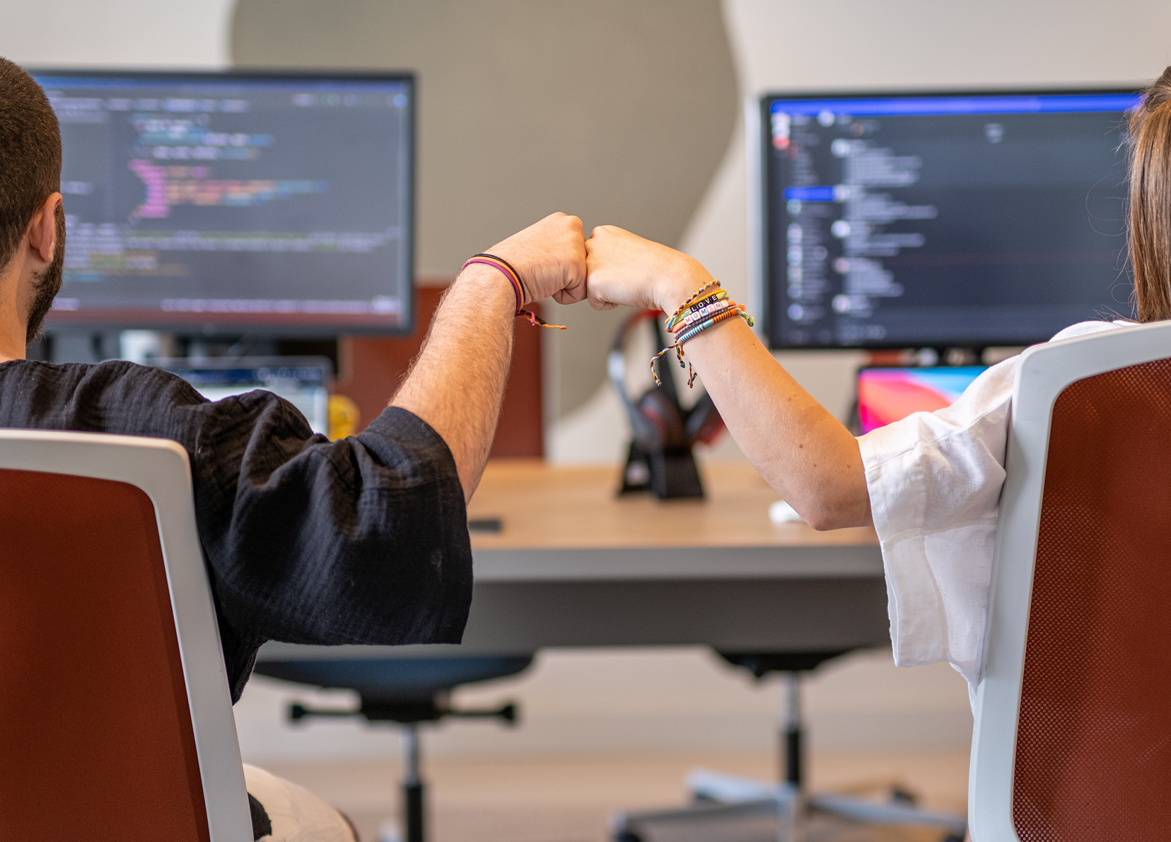 A group of five people chatting and laughing in a modern office.