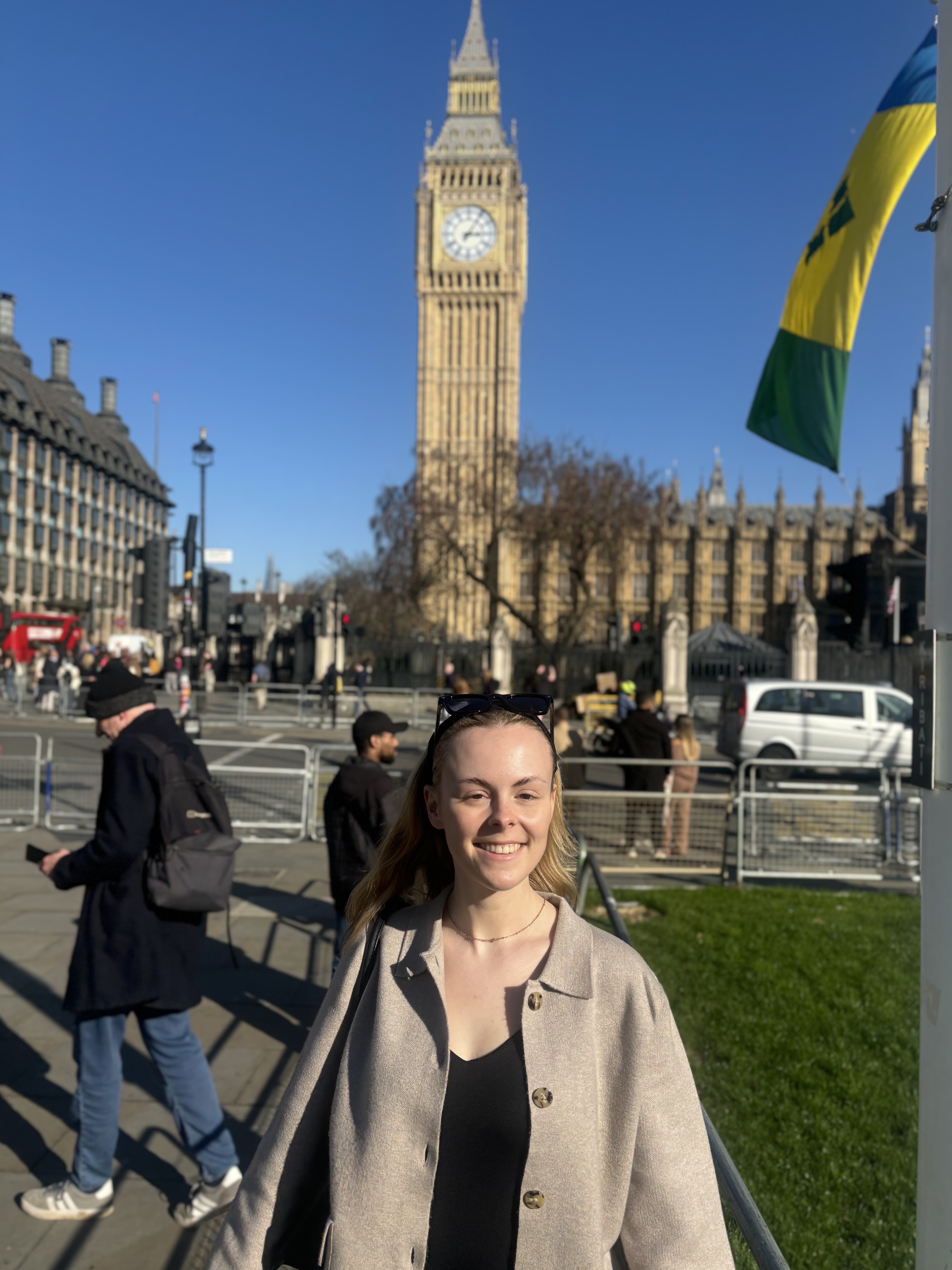 Smiling Jodie with sunglasses on her head standing near Big Ben in London on a sunny day.