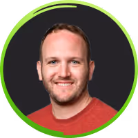 Smiling man with short hair and beard wearing a red shirt on a dark background with a green circular border.