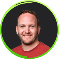 Smiling man with short hair and beard wearing a red shirt on a dark background with a green circular border.