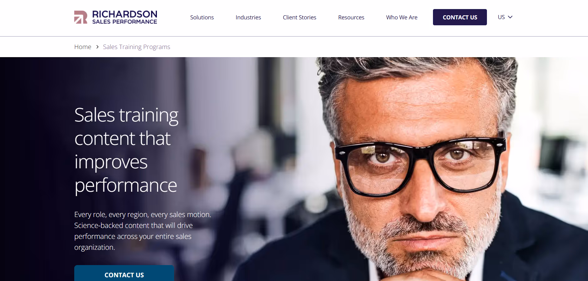 Close-up of a middle-aged man with gray hair and beard wearing black glasses looking intently at the camera.