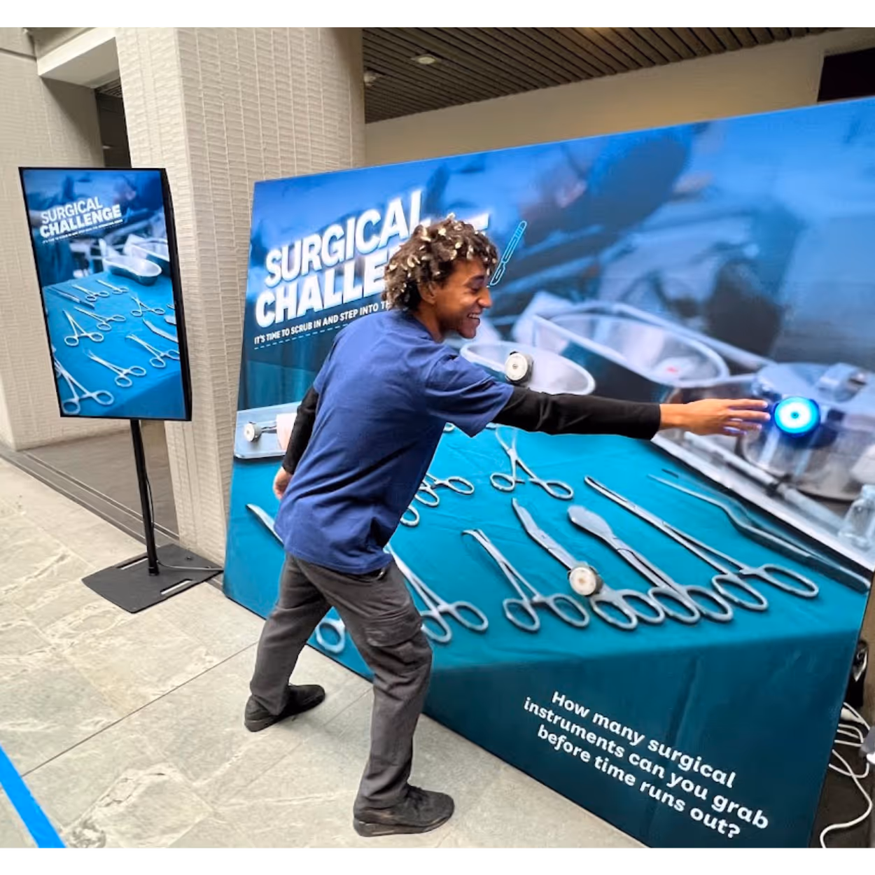 Person reaching to grab a glowing blue button on a surgical instruments challenge display board.