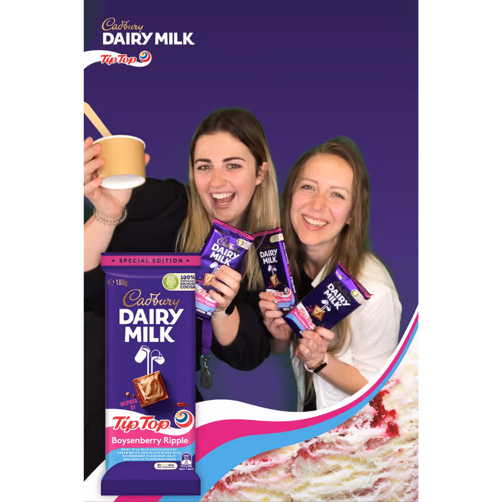 Two women smiling holding Cadbury Dairy Milk Tip Top Boysenberry Ripple chocolate bars and cup with spoon.