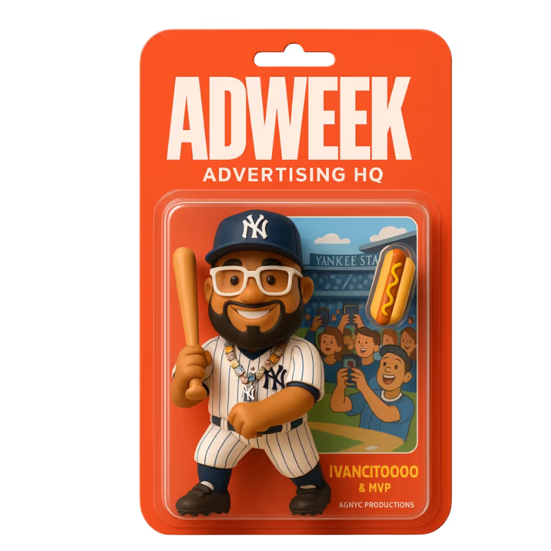 Toy figure of a smiling baseball player in a Yankees uniform holding a bat, packaged on ADWEEK card.