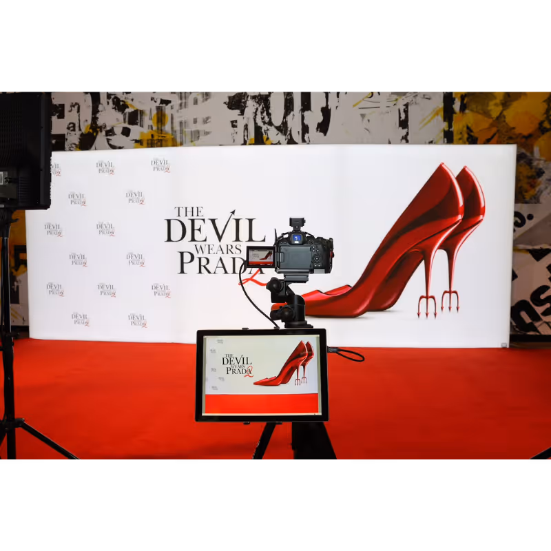 Photography setup with camera and screen focused on a banner of devil-red high heels with pitchfork heels.