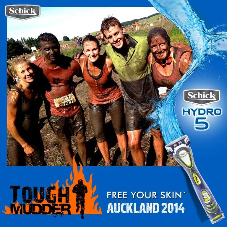 Five muddy participants smiling and posing outdoors after Tough Mudder Auckland 2014 event.