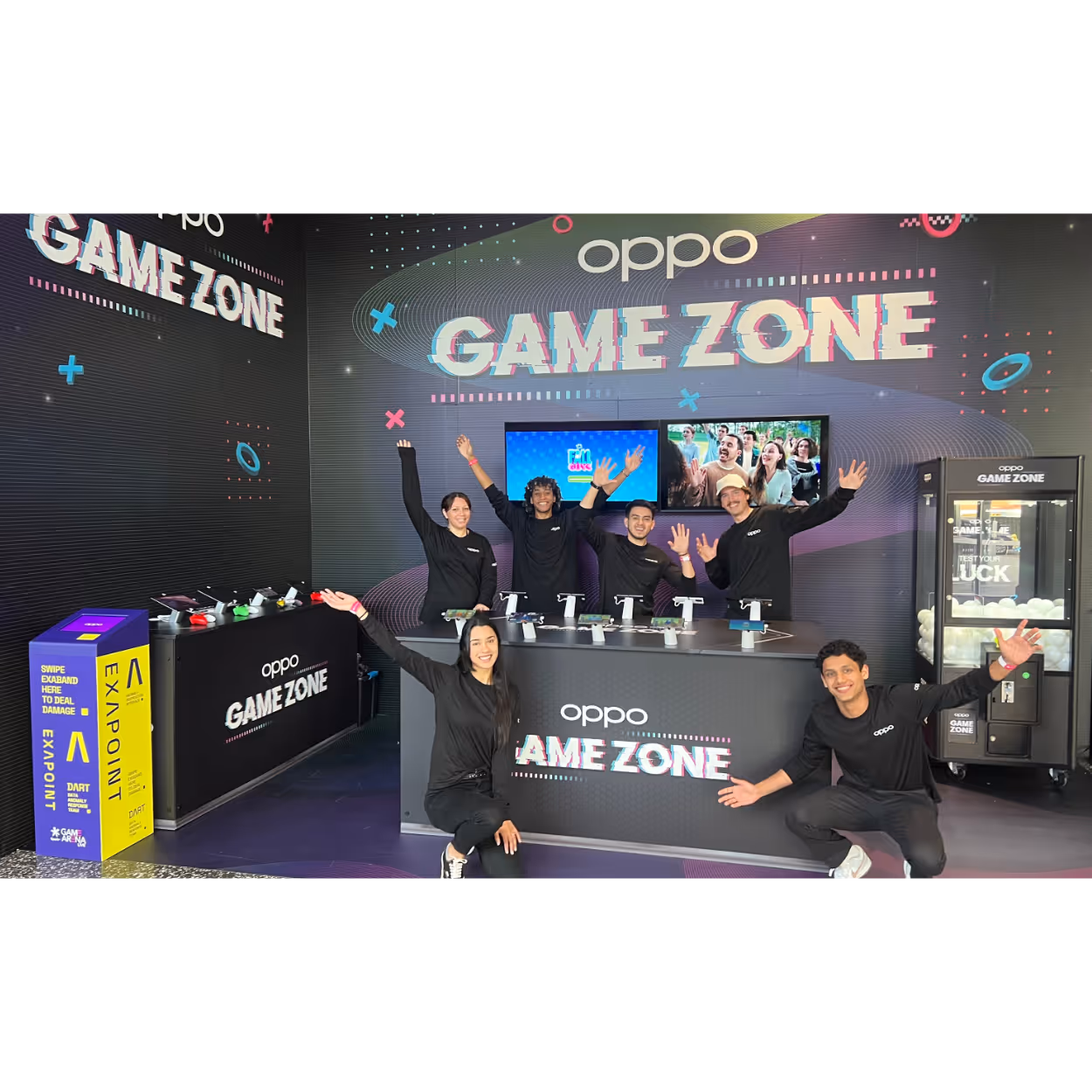 Six people in black Oppo shirts pose with raised hands in a colorful Oppo Game Zone event booth.