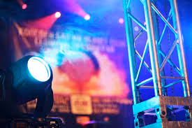 Blue stage spotlight shining with smoke and metal truss frame in the background.