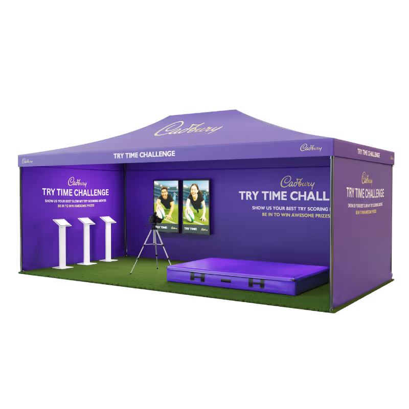Purple Cadbury Try Time Challenge tent with interactive screens and a soft landing mat on green floor.