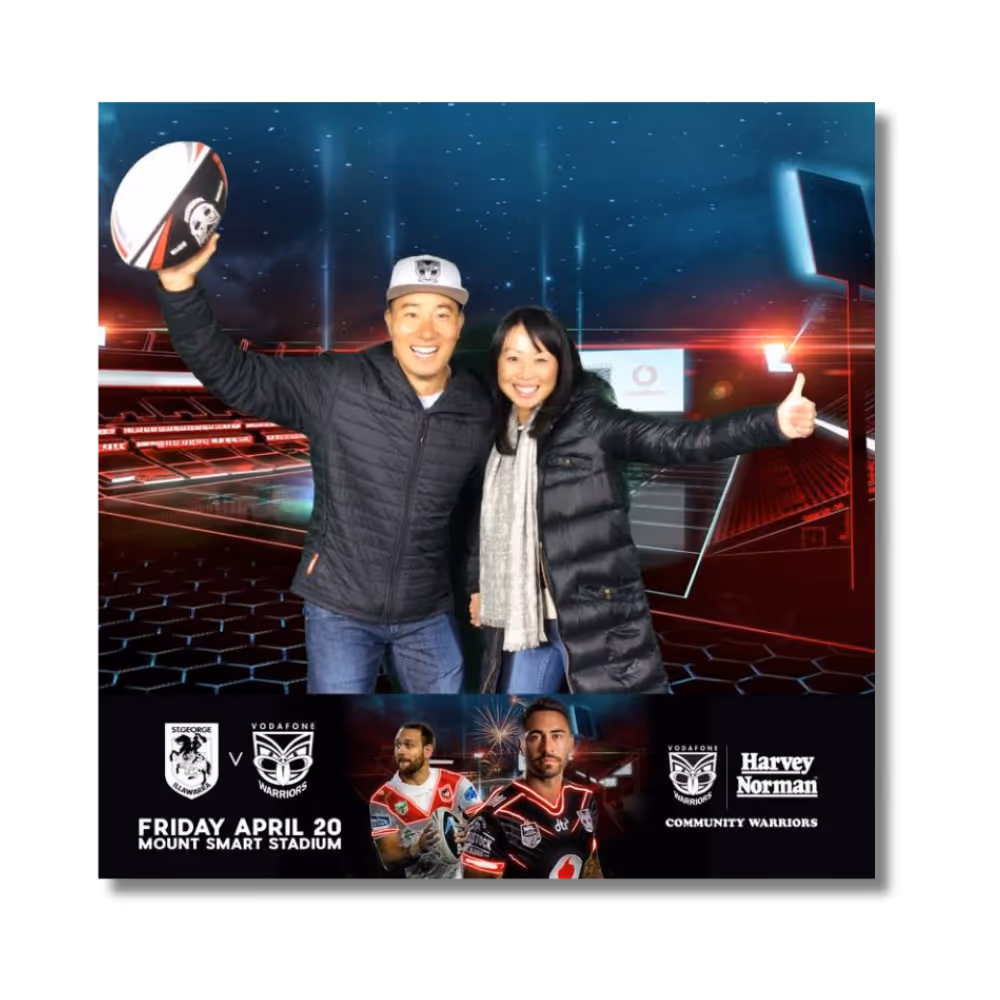 Smiling man and woman posing with rugby ball in front of digital stadium and event info.