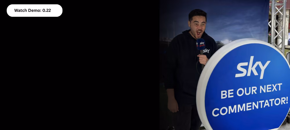 Man holding Sky Sports microphone beside sign saying 'Sky Be Our Next Commentator!'