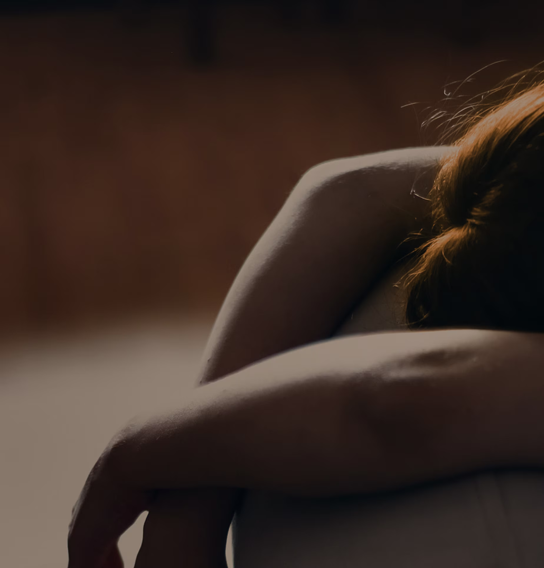 Image of a woman on a couch with her arms draped over the back and looking bored.