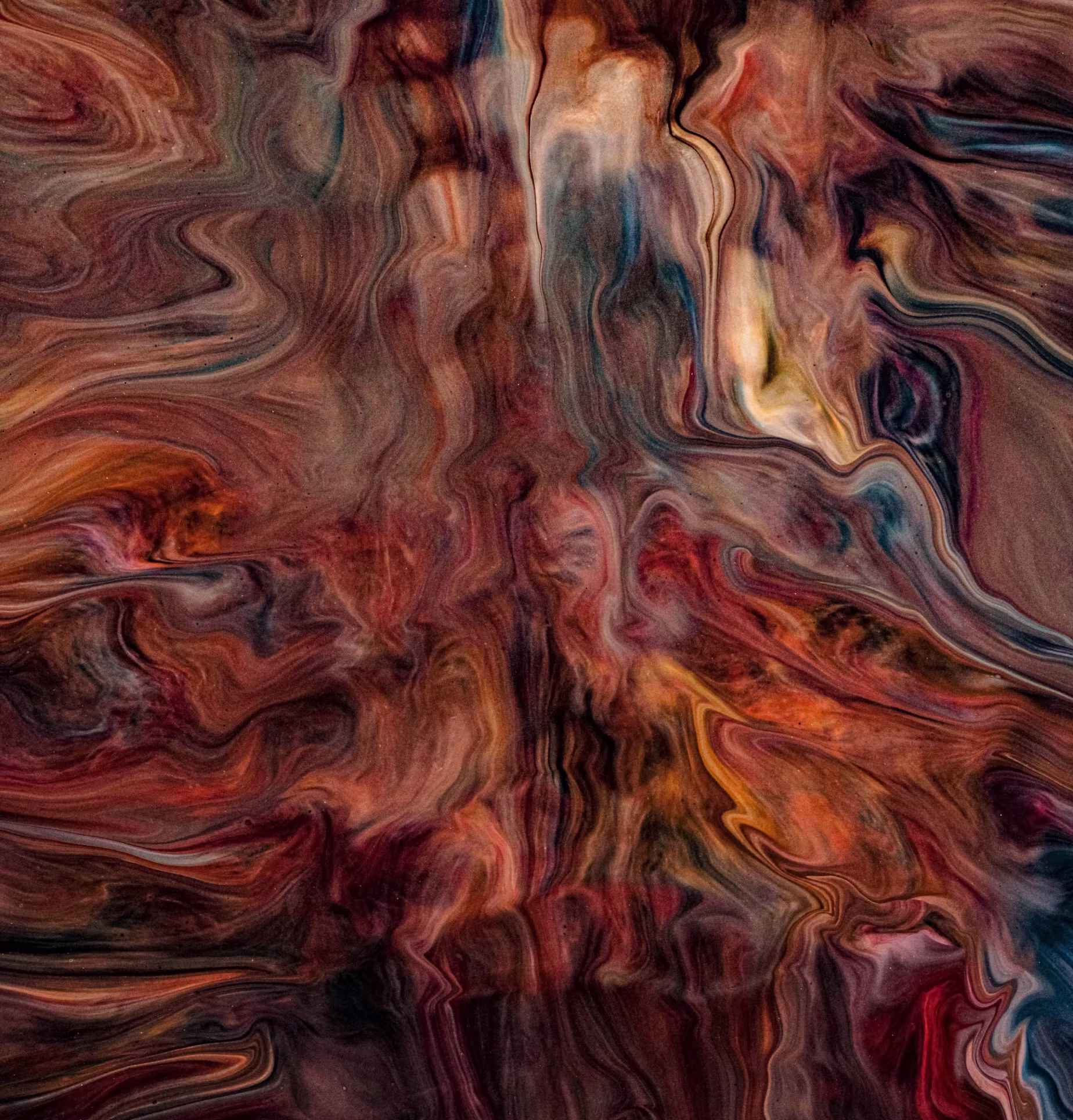 An abstract image featuring swirling patterns of deep reds, oranges, blues, and browns, resembling marbled paint or polished stone.