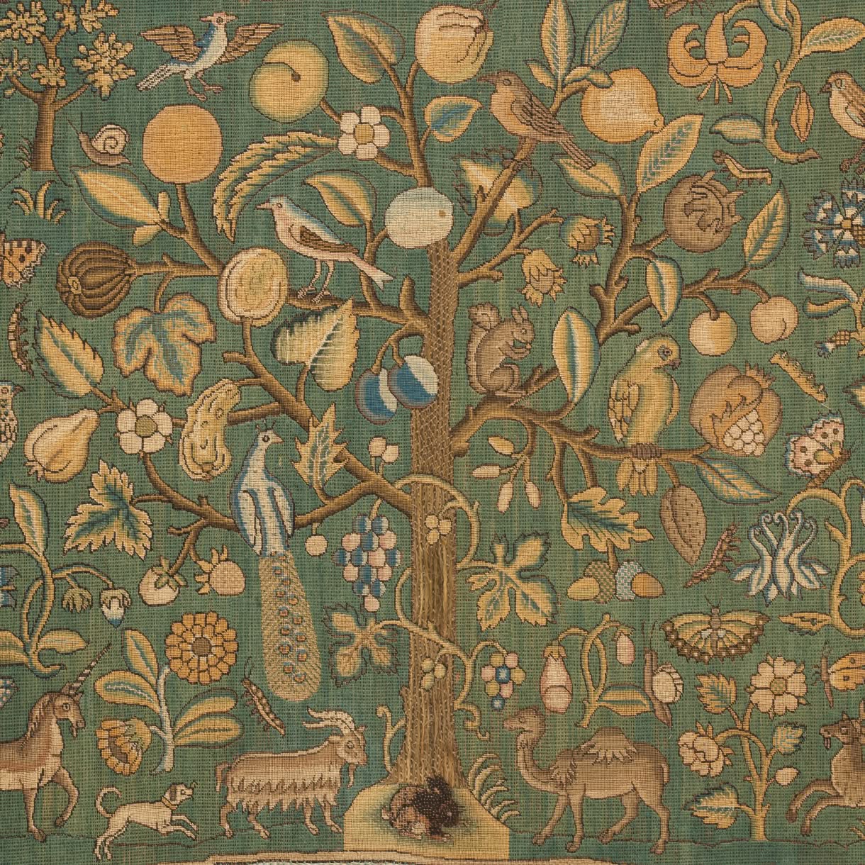 A richly patterned textile shows a central tree filled with fruits and birds, surrounded by flowers and animals including a peacock, goat, camel, squirrel, and deer on a green field.