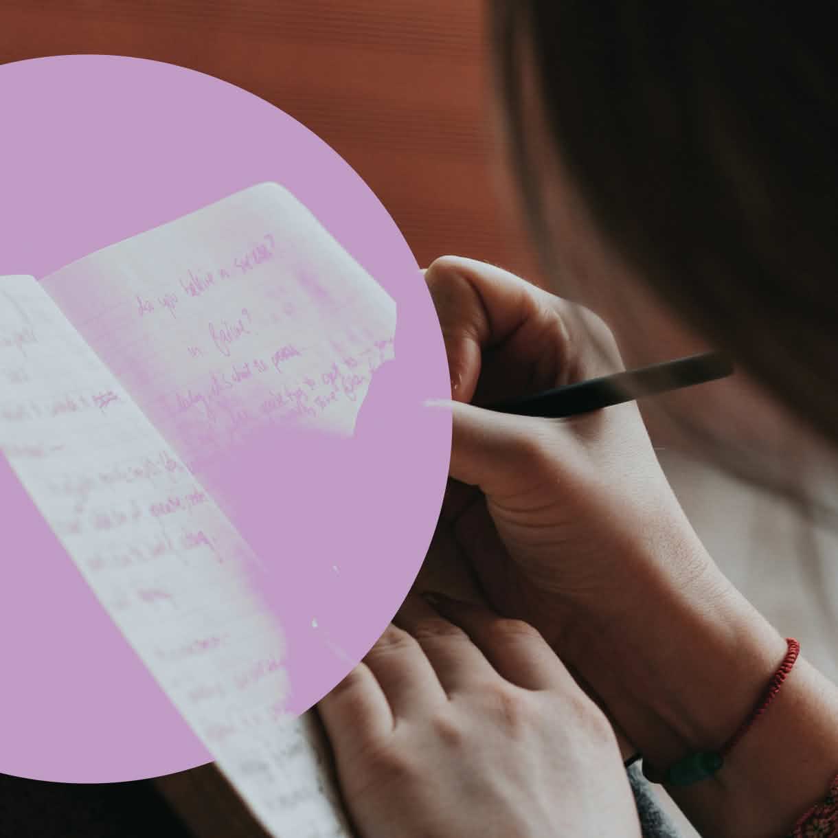 Close-up of a person writing with a black pen in an open notebook filled with handwritten notes. A large translucent lavender circle overlays the left side of the image, partially obscuring the notebook pages.