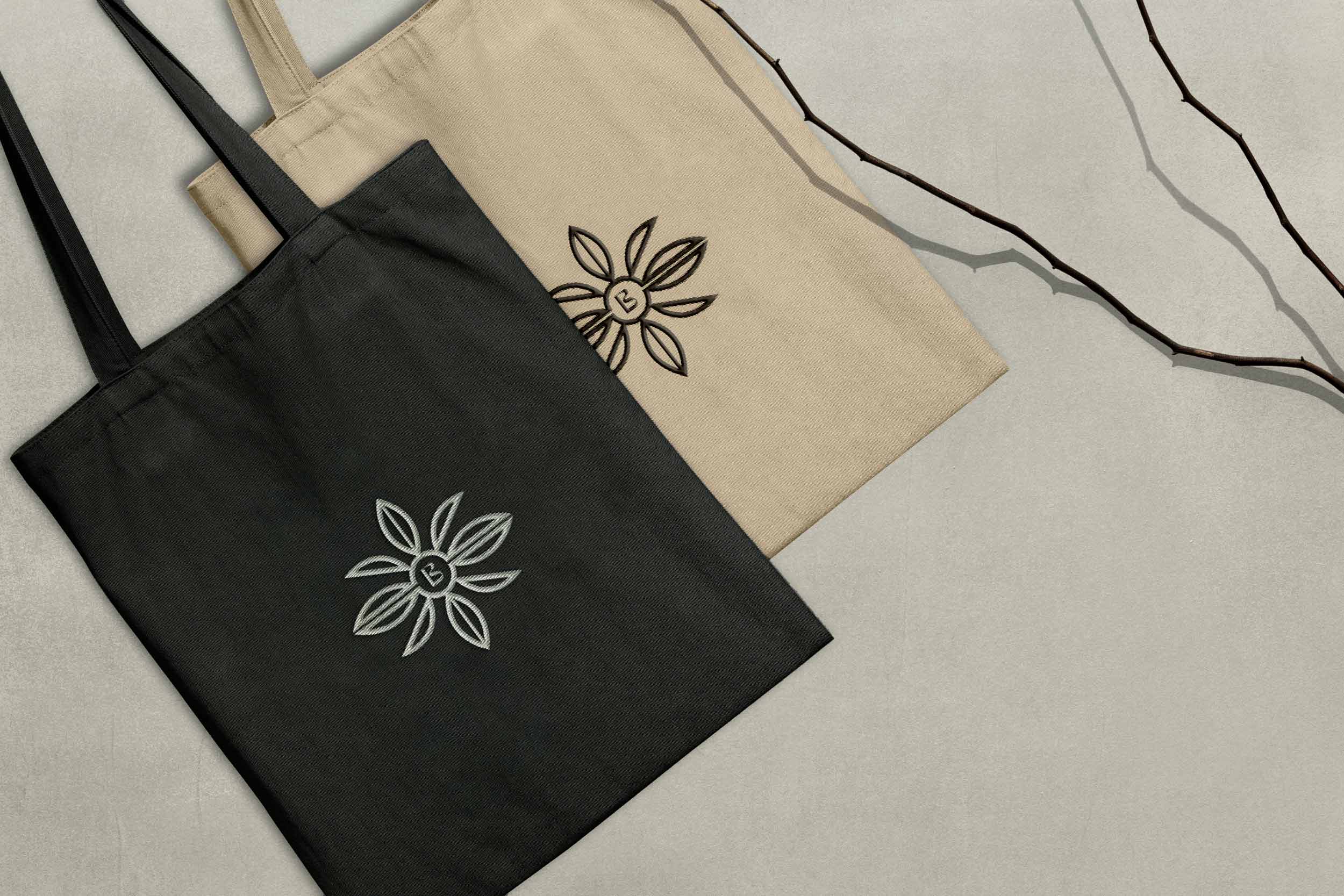 Blomst icon embroided onto a black and beige tote bag. 