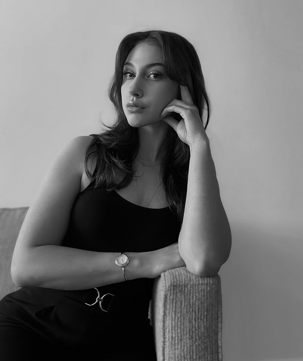 Emily sitting on a couch, leaning on her arm. Black and white photo